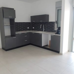 מטבח נקי עם ארונות כהים ורצפה בהירה