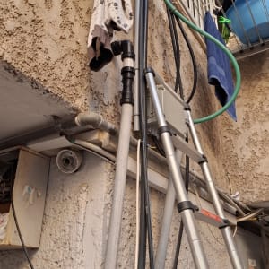 סולם וצינורות ליד קיר חיצוני עם בגדים תלויים