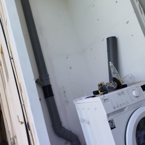 צינור פלסטיק וכלי עבודה ליד מכונת כביסה