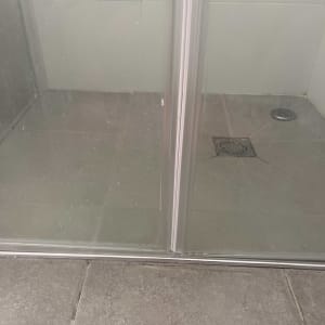 מקלחון עם דלת זכוכית ורצפת אריחים