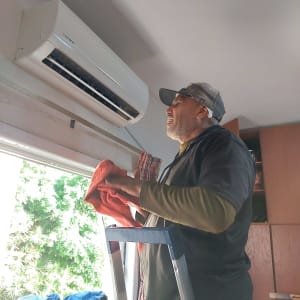 אדם מנקה מזגן עם מטלית אדומה