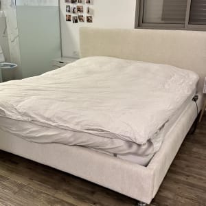 מיטה עם מצעים לבנים בחדר שינה