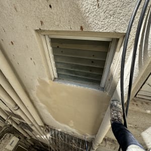אדם עומד על צינור ליד חלון עם תריסים