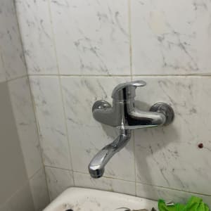 ברז מים על קיר עם אריחים לבנים