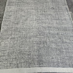 שטיח על רצפה אפורה עם נעל שחורה בקצה