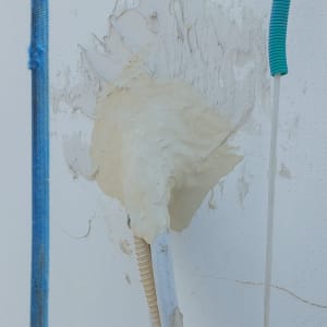 צינור מכוסה בחומר איטום על קיר לבן