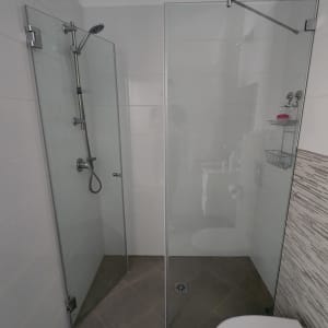 מקלחת עם דלתות זכוכית, ראש מקלחת ומדף סבונים