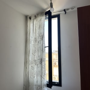 וילון תלוי על חלון עם מנורה בתקרה