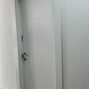 דלת לבנה עם ידית מתכת על קיר לבן