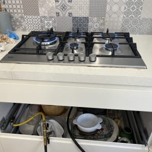 כיריים גז עם להבות כחולות ומגירות פתוחות מתחת