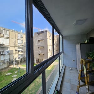 חלונות אלומיניום גדולים במרפסת עם סולם וכלי עבודה