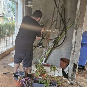 אדם עובד על צינורות מים עם כלי עבודה