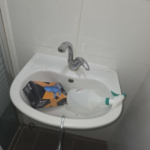 כיור עם ברז, בקבוק ריסוס ואריזת כפפות
