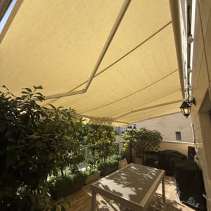 מרפסת עם סוכך צל, שולחן וכיסאות, צמחים מסביב