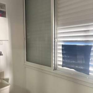 חלון עם תריסים וסינק בחדר שירותים