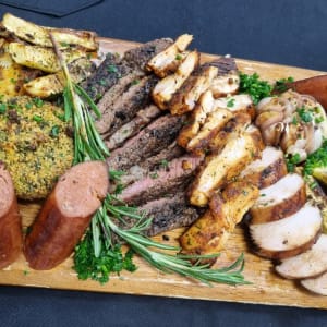 מגש עץ עם בשרים צלויים, נקניקיות ועשבי תיבול