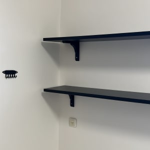 שתי מדפים שחורים מותקנים על קיר לבן