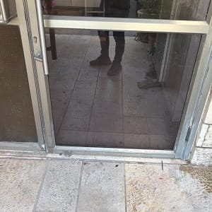 דלת זכוכית בכניסה למבנה עם מסגרת אלומיניום וידית נירוסטה