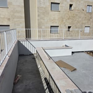 מרפסת עם מעקה לבן ורצפת בטון