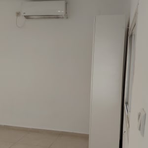 חדר עם מזגן על הקיר וארון לבן