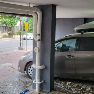 צינור לבן מחובר לעמוד חניה עם רכב אפור