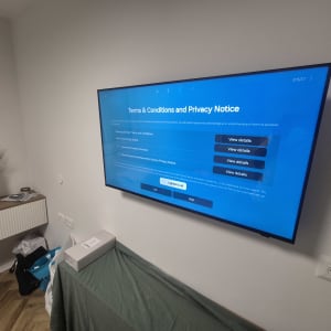 טלוויזיה מותקנת על קיר בחדר עם שולחן קטן