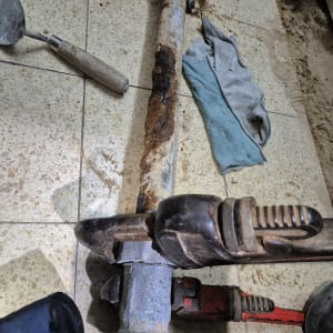 צינור חלוד עם מפתח צינורות על רצפה