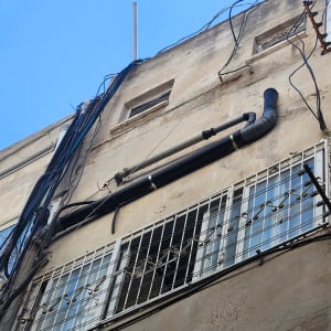 צנרת וחוטי חשמל על קיר חיצוני של בניין