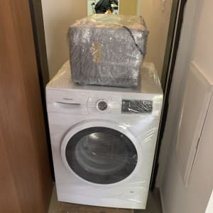 מכונת כביסה ופריט נוסף עטופים בניילון על עגלה קטנה