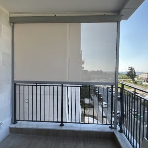 מרפסת עם סוכך גלילה חצי שקוף על מעקה מתכת