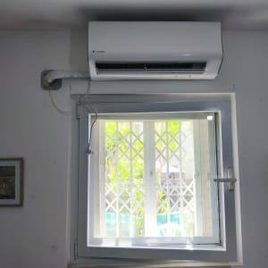 מזגן מותקן מעל חלון עם סורג לבן