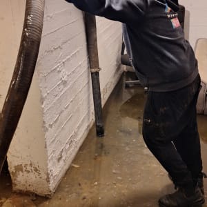 אדם מחזיק צינור גדול בחדר מוצף מים