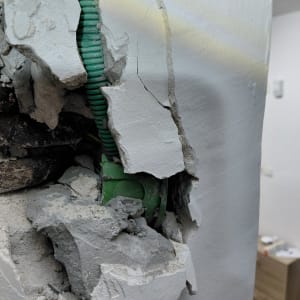 צינור חשמל ירוק בקיר שבור