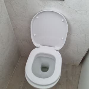 אסלה לבנה בחדר אמבטיה עם קירות אריחים אפורים