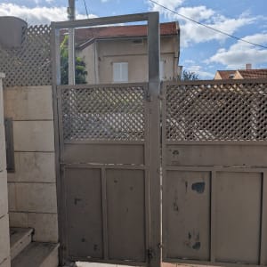 שער מתכת חיצוני עם רקע של שמיים ובתים