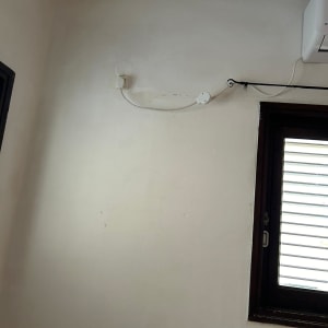 יחידת מזגן מותקנת על קיר עם חוט חשמל