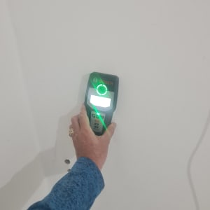 יד מחזיקה מכשיר בוש על קיר לבן