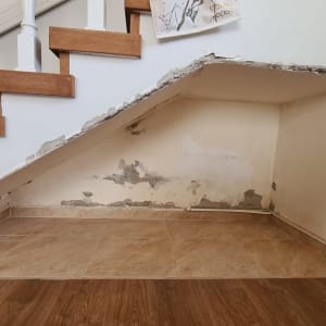 קיר מתקלף מתחת למדרגות עם סימני רטיבות