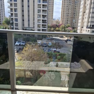 מעקה זכוכית עם נוף לבניינים ועצים