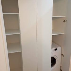 ארון לבן עם מדפים ומכונת כביסה