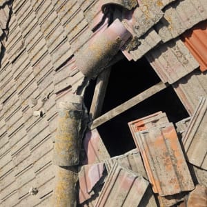 רעפים שבורים על גג עם חור גדול