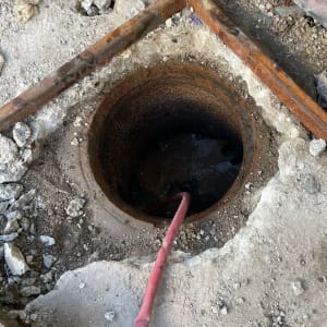 צינור אדום נכנס לפתח ביוב באתר בנייה