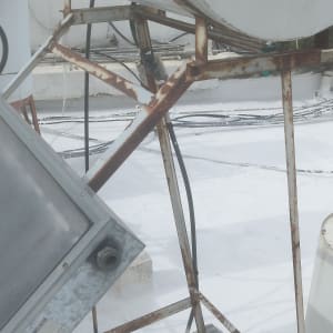 מיכל מים על גג עם צינורות וחלודה