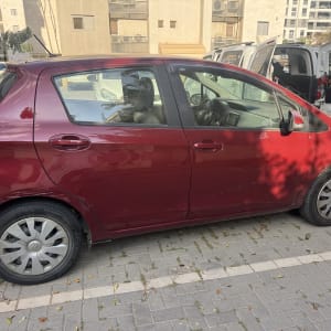 רכב אדום חונה בחניון עם כלי ניקוי ברקע