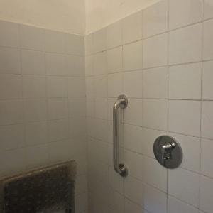 פינת מקלחת נגישה הכוללת ראש טוש, ברז אינטרפוץ, ידית אחיזה ותעלת ניקוז
