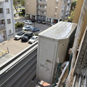 יחידת מזגן חיצונית מותקנת על מרפסת בניין מגורים
