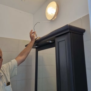 אדם מחזיק חוט חשמל ליד מנורה על הקיר