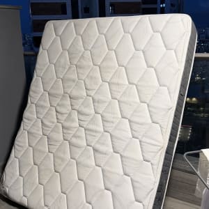 מזרן עומד על מרפסת עם רקע של בניינים בלילה