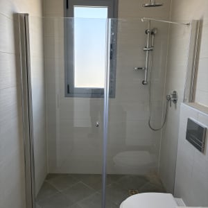 מקלחת עם דלת זכוכית וראש מקלחת