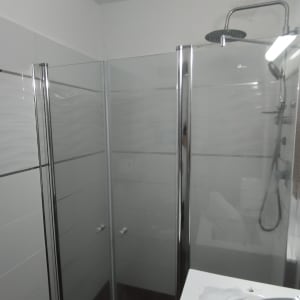 מקלחת עם דלתות זכוכית וברז גשם